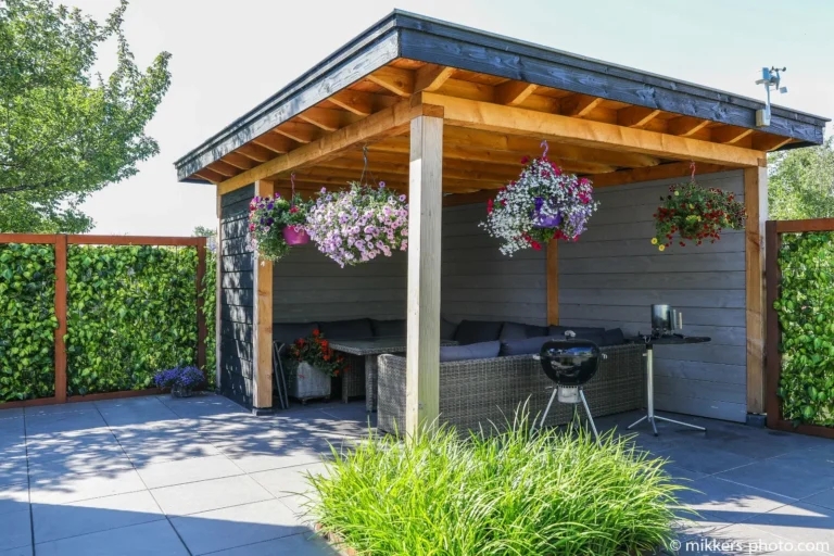 Houten overkapping met weelderige hangplanten in een ontworpen tuin
