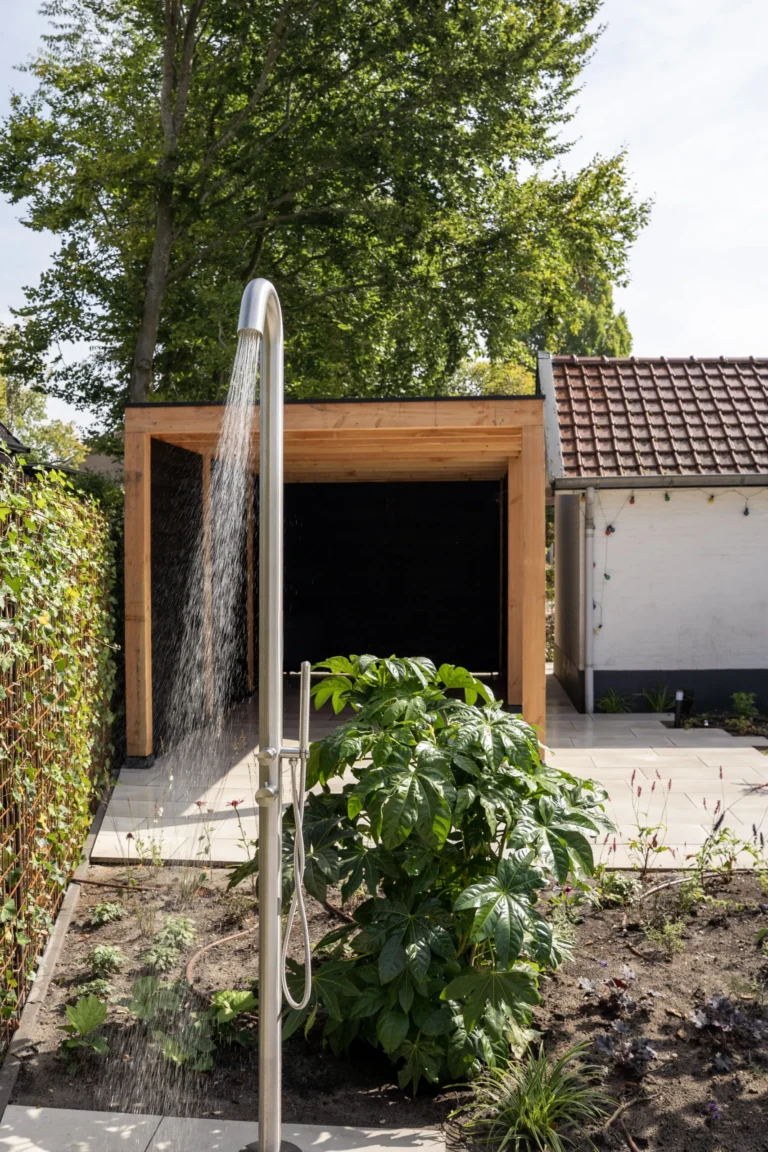 Buitendouche met hout en groen in een moderne wellness-tuin
